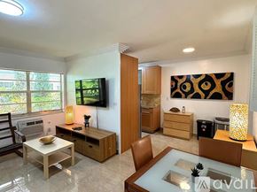 Miami Beach condo for rent - A modern living room with a glass table and a television.