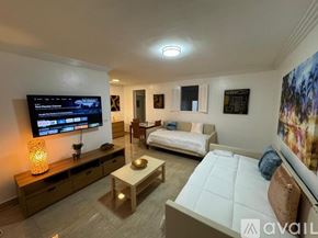 Miami Beach condo for rent - A living room with a flat screen TV mounted on the wall.