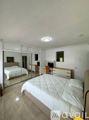 Miami Beach condo for rent - A bedroom with a large bed and a mirrored closet.