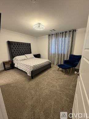 Las Vegas townhouse for rent - A bedroom with a large bed and a blue chair.