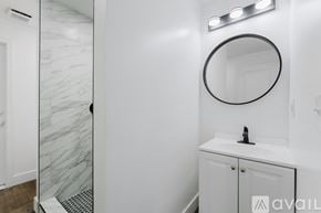 Ypsilanti house for rent - A bathroom with a marble wall and a round mirror.