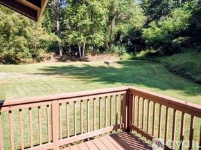 Candler house for rent - A wooden deck overlooks a grassy field and trees.