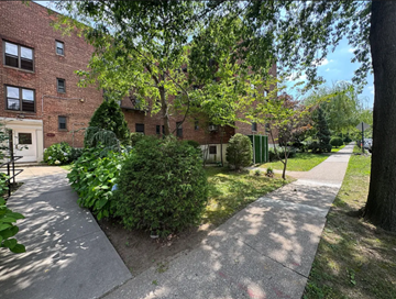 Queens apartment for rent - A tree-lined walkway leads to a brick building.