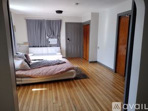 Oshkosh apartment for rent - A bedroom with a bed, a window with curtains, and a wooden floor.