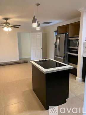 Boynton Beach condo for rent - A kitchen with a black island and a white door in the background.