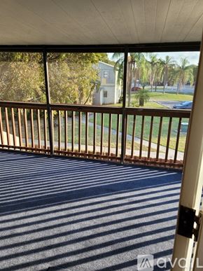 Boynton Beach condo for rent - A balcony with a metal railing and a view of a street and trees.