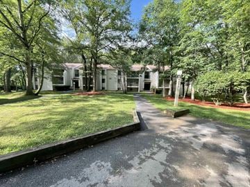 State College apartment for rent - A white building surrounded by trees and a driveway.