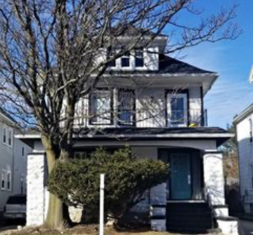 Buffalo apartment for rent - A white house with a black roof and a balcony.