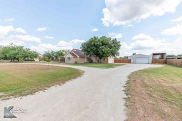 Abilene house for rent - A gravel driveway leads to a house with a white garage door.