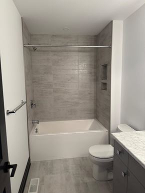 London house for rent - A bathroom with a toilet, tub, and sink.