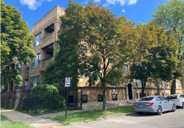 Chicago apartment for rent - A street view with a car parked on the side of the road and a building in the background.