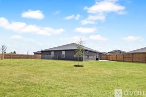 Killeen apartment for rent - A grassy field with a wooden fence and two buildings in the background.