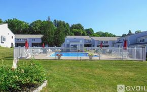 Canton condo for rent - A pool surrounded by a fence and chairs with a building in the background.
