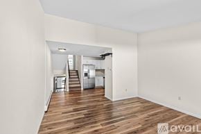 Canton condo for rent - A spacious room with wooden floors and white walls, leading to a kitchen area.