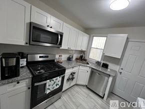 Ventnor City house for rent - A kitchen with white cabinets and a black stove top.