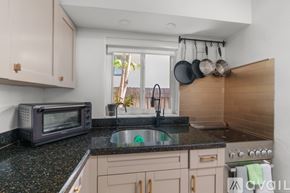 Fort Lauderdale apartment for rent - A kitchen with a black microwave, black granite countertop, and a window.