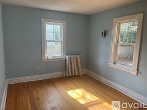 Hopewell house for rent - A room with light blue walls, a white window, a white radiator, and a wooden floor.