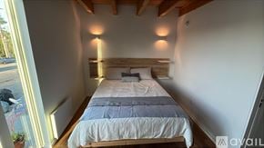 Seattle townhouse for rent - A bedroom with a large bed and a window overlooking a parking lot.
