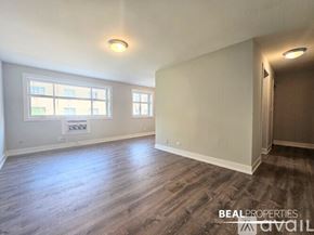 Chicago condo for rent - A spacious room with a large window and a wooden floor.