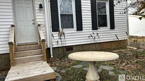 Louisa apartment for rent - A white house with a wooden staircase and a round table.