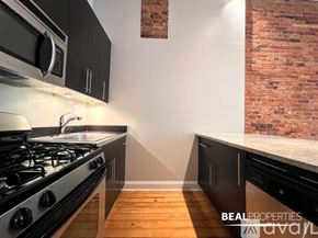 Chicago condo for rent - A spacious room with wooden flooring and a fireplace.