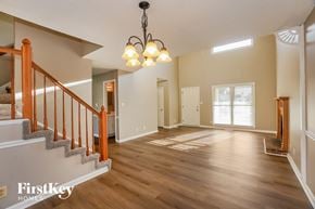 Clarksville house for rent - A well-lit, spacious room with wooden floors and a staircase with a wooden railing.