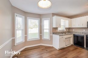 Clarksville house for rent - A kitchen with wooden floors and white cabinets.