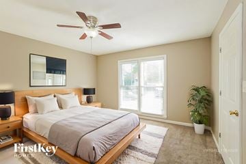 Clarksville house for rent - A bedroom with a bed, a ceiling fan, and a mirror on the wall.