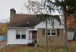 Akron apartment for rent - A small white house with a brown roof and a red star on the wall.