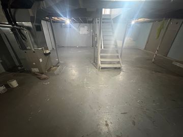 Akron apartment for rent - A dimly lit industrial space with a staircase and machinery.