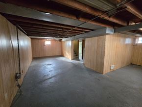 Hammond house for rent - A sparsely furnished room with wooden walls and a concrete floor.