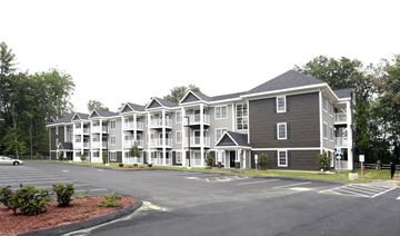 Bedford apartment for rent - A large apartment complex with a parking lot in front.
