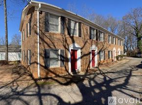 Spartanburg apartment for rent - A brick building with a red door is surrounded by bare trees.
