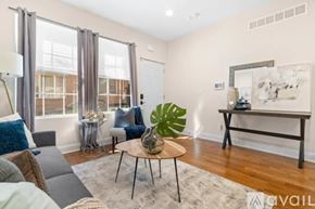 Philadelphia house for rent - A living room with a grey couch, a wooden coffee table, and a large window with curtains.