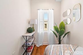 Philadelphia house for rent - A bedroom with a bed, a plant, a lamp, and a mirror on the wall.