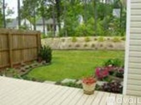 Richmond townhouse for rent - A wooden deck overlooks a garden with a fence and a wall.