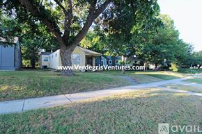 Fort Worth house for rent - A tree in a grassy area with a house and a trailer in the background.