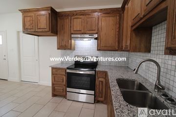 Fort Worth house for rent - A kitchen with wooden cabinets and a stainless steel oven.