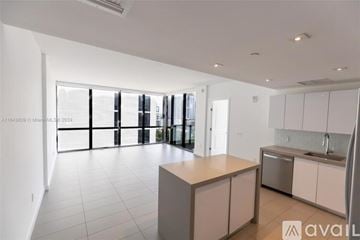 Miami condo for rent - A modern kitchen with white cabinets and a central island.