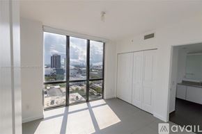 Miami condo for rent - A spacious room with large windows overlooking a cityscape.