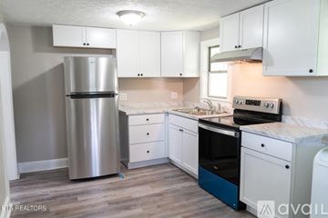Knoxville apartment for rent - A kitchen with a stainless steel refrigerator, white cabinets, and a wooden floor.