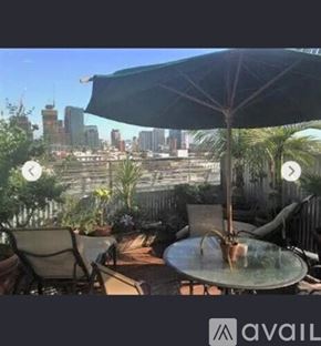 Los Angeles apartment for rent - A patio with a table, chairs, and an umbrella overlooking a city skyline.