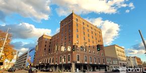 Elmira apartment for rent - A large red brick building with many windows is in the middle of a street.