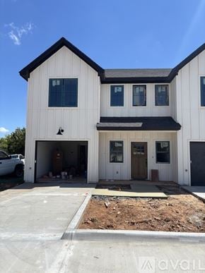 Poolville townhouse for rent - A modern house with a black roof and white walls is surrounded by a well-manicured lawn.