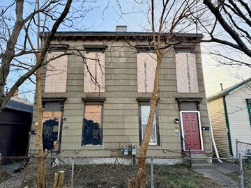 Louisville apartment for rent - A house with boarded up windows and a red door.