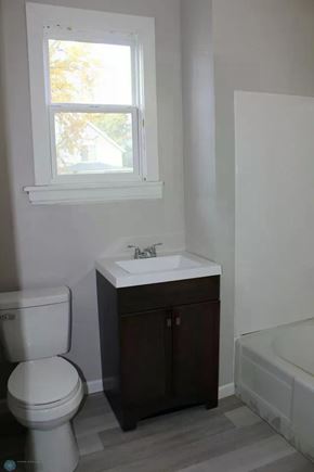 Fargo house for rent - A white toilet sits next to a sink in a bathroom.