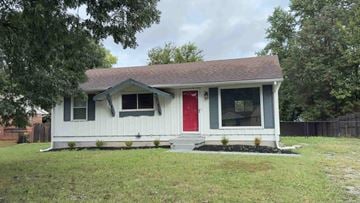 Clarksville house for rent - A small white house with a red door is surrounded by a grassy area.