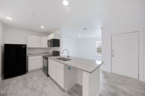 San Antonio apartment for rent - A kitchen with a black fridge, white cabinets, and a granite countertop.