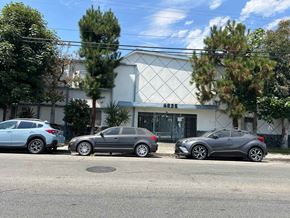 Cudahy apartment for rent - Three cars parked in front of a white building with a black gate.