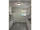 Mobile house for rent - A kitchen with white cabinets and a white door.